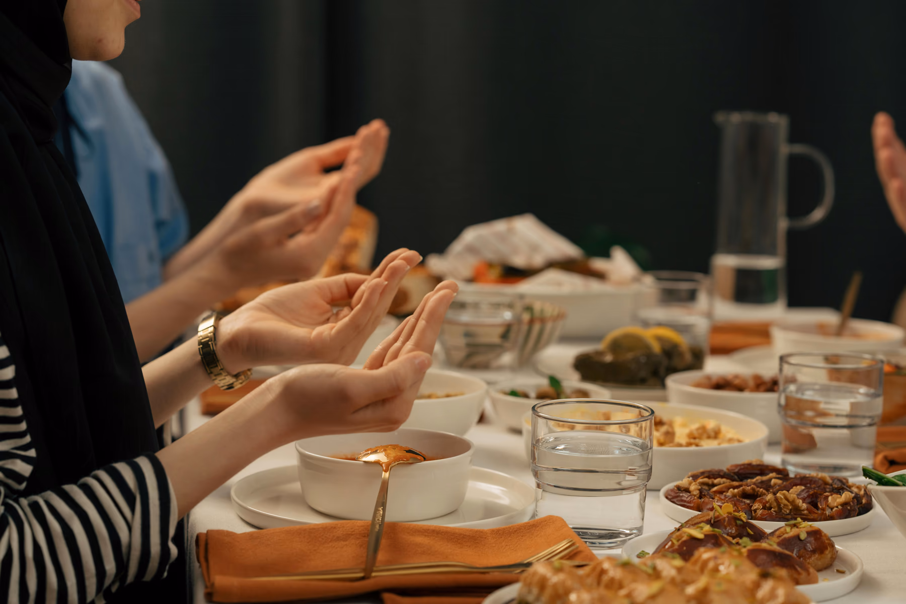 Family gathered in prayer around an Eid table with dates and food